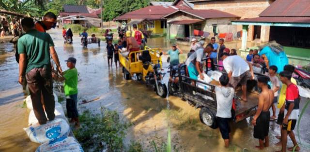 Poto : warga Dusun Kenangkung sedang menambal sisi atas tanggul dangan menggunakan karung yang diisi dengan pasir atau tanah.Dok : SWARA45.COM/Afrizal]