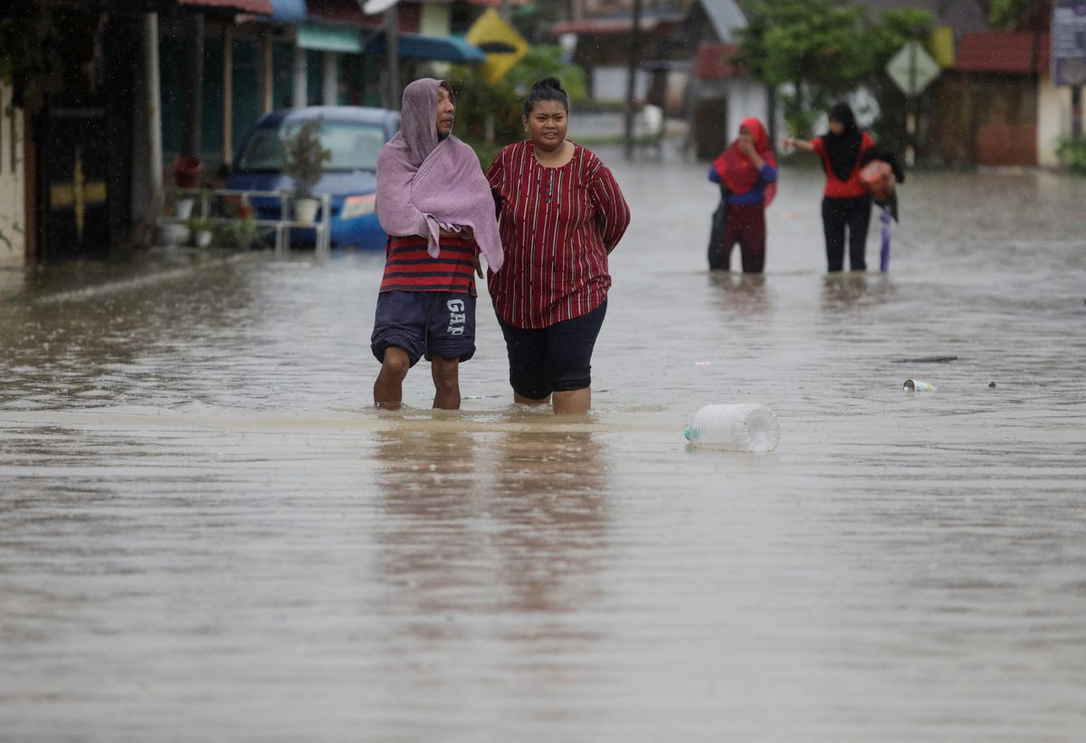 Orang-orang menyeberangi area pemukiman yang terendam banjir di Yong Peng, Johor, Malaysia 4 Maret 2023. Dok : REUTERS/Hasnoor Hussain)