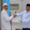 Sekda Aceh Tamiang. Drs. Asra menyerahkan bantuan Baitul Mal untuk BKM Baiturrahman di Kampung Marlempang, Bendahara. Dok : Prokopim/SWARA45.COM/Afrizal]